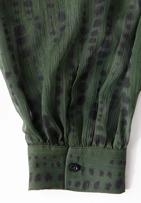 Grüner, transparenter Ärmel mit schwarzen Punkten und Manschette.